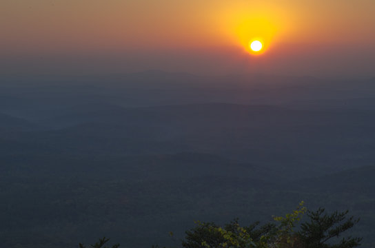The sun prepares to dip below the horizon beyond the valleys visible from Cheaha State Park in Alabama, USA