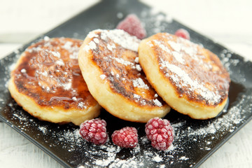 Cottage cheese pancakes on dark plate over white rustic wooden table. Healthy food for breakfast. Soft focus.