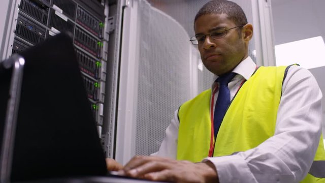Computer engineer carrying out checks in a data center server room.