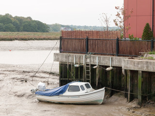 parking white private boat in mud at end of dock