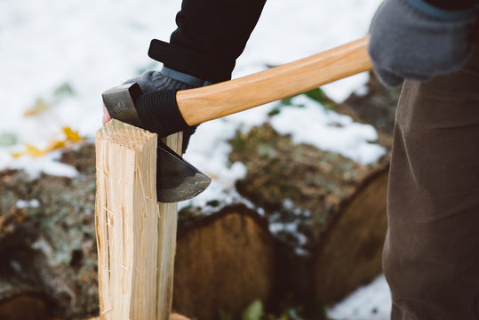 Detail shot of a man chopping wood with an ax.