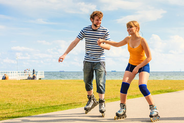 Obraz premium Young couple on roller skates riding outdoors