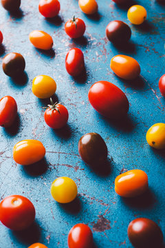 Variety of cherry tomatoes on blue background.