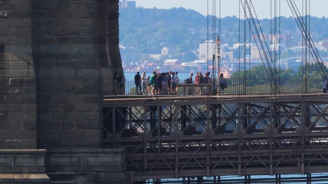 An extreme long establishing shot view of pedestrians and tourists on the Brooklyn Bridge walkway.  	