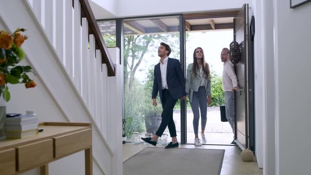 Happy couple with real estate agent, viewing modern home to buy or rent