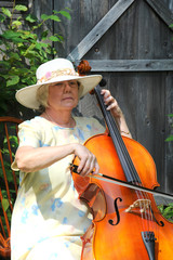 Mature female cellist performing on her cello outdoors. © oscar williams