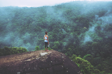 Asian women travel relax in the holiday.  Standing hands on a rocky cliff. Wild nature wood on the mountain.