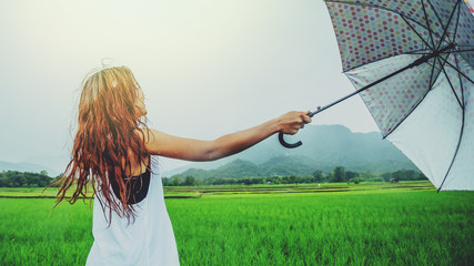 Fototapeta na wymiar Asian women travel relax in the holiday. Women stand in rain umbrellas. On the meadow During the rainy season.Thailand