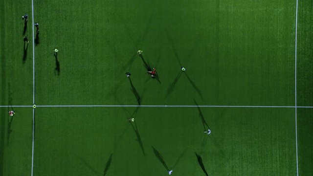 Aerial view of players on 3 soccer pitches playing floodlit games at night