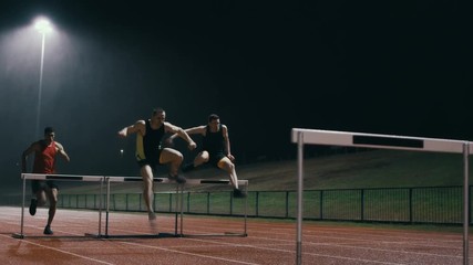 Competitive athletes running & jumping over hurdles at athletics track - Powered by Adobe