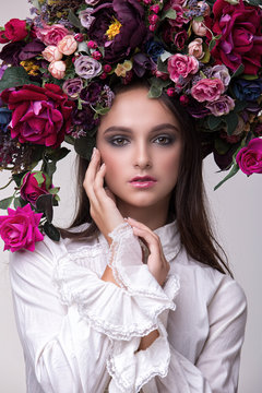 Portrait of a girl model in a beautiful image with a wreath of flowers on her head in a photo studio. Fashion, style, beauty, portrait.