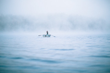 Mystical woman in row boat on a foggy New England morning