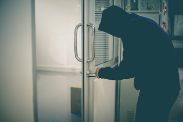 Burglar striving to open a window to a house