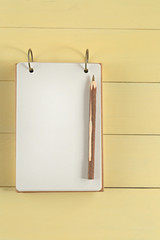Notebook  Mockup. mockup with notepad  with wooden  pen  on yellow wooden background. Blank empty notepad. Flat lay, top view, copy space.