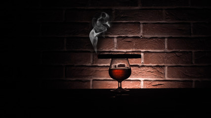 Glass of cognac with cigar in stone cellar