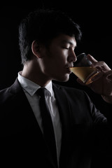 portrait of Asian man in black formal suit with a glass of whisky