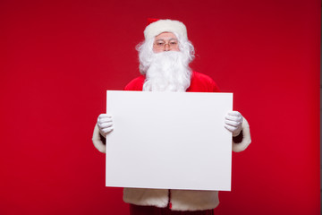 Santa Claus pointing in blank advertisement banner isolated on red background with copy space