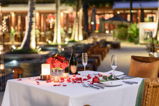 Special romantic candle light dinner table set up by the pool for couple with a bottle of champaign