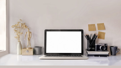 Mock up of blank screen laptop on the desk. Work space Mock up white tabletop vintage camera and pencils on white wood desk with copy space for products display montage. work space concept.