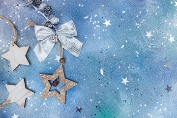 star shaped wooden christmas decorations and silver bow on blue background