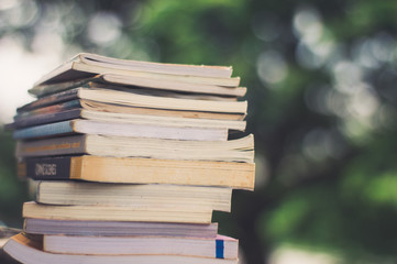 Book stack on the table over the background of the blurry outdoor location.