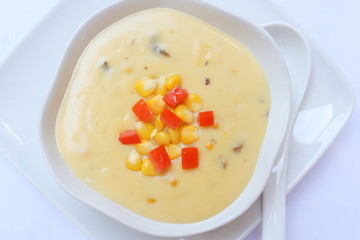 Corn soup and tomato in white bowl on white dish .closeup