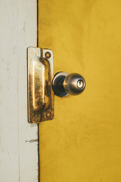 Close up door knob and brightly colored yellow door on building exterior