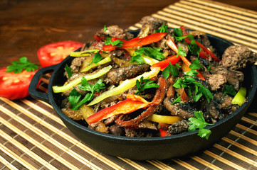 Fried chicken liver in a cast iron skillet with vegetables
