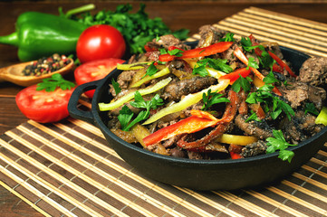 Fried chicken liver in a cast iron skillet with vegetables