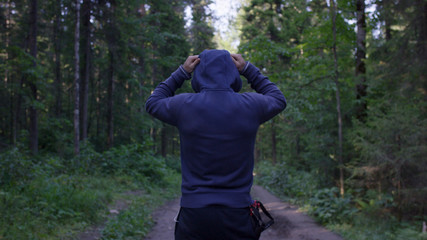 Person in a hood standing. Man in the hood in the woods. Sport in the forest on the nature