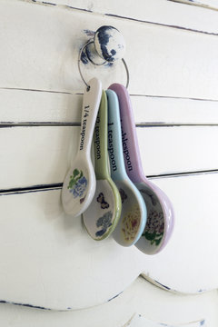 Domestic measuring spoons hanging on an antique kitchen cupboard