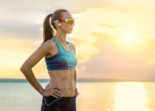 Running woman in sport sunglasses. Female runner with her smartp