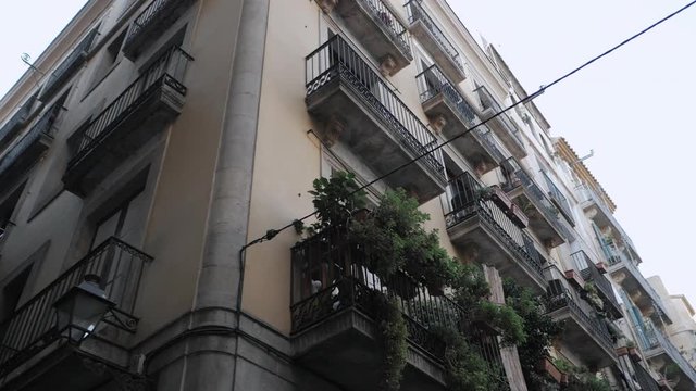 Apartment building streets in Barceloneta area. House with balconies in Barcelona's Gothic Quarter. Facades of old houses in the narrow streets of Barcelona. Traveling concept. Slow motion.