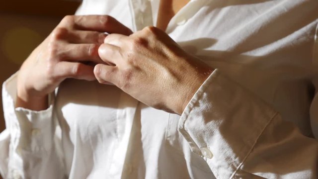 close-up, details. a woman unfastens the top button on her white shirt, removes it. 4k, slow motion
