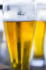 Two glasses of beers on a wooden table.