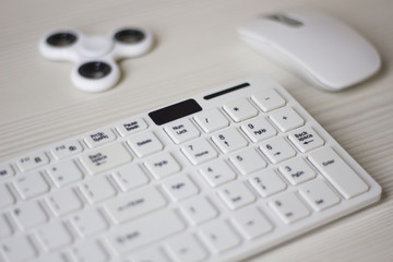 white computer mouse, spinner and keyboard on a white table, business concept