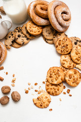 Culinary background of home-baked shop, top view free space. Wholegrain scones and baked rolls laying in circle near bottles of milk on white table. Concept of delicious breakfast