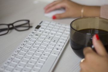 hands business woman holding coffee Cup sitting at Desk and working on a white keyboard