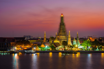 Fototapeta premium Wat Arun Temple beside Chao Phraya River at twilight time in Bangkok, Thailand. One of the most famous place of Thailand's landmarks. Light reflection on smooth water.