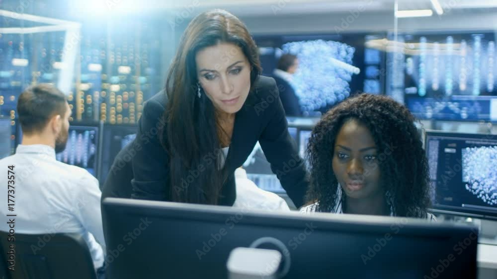 Poster Female Team Leader Consults Young Computer Engineer. They Work in a Crowded Office on a Neural Network/ Artificial Intelligence Project. 
