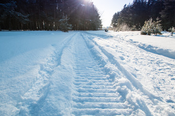 Close-up of a snowmobile trace on snow and sun