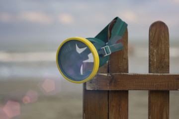 mask for snorkeling at the small brown fence against the sea