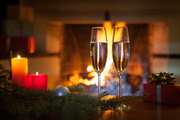 Two glasses with champagne in front of the fireplace. New Year. Christmas.