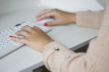 Female hands typing on white computer keyboard