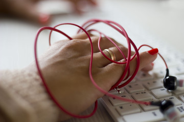 female hand wrapped headphones in red print on a white keyboard keyboard