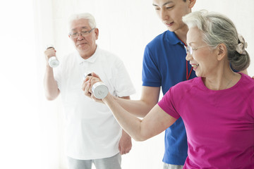 An elderly couple training dumbbell training with a trainer