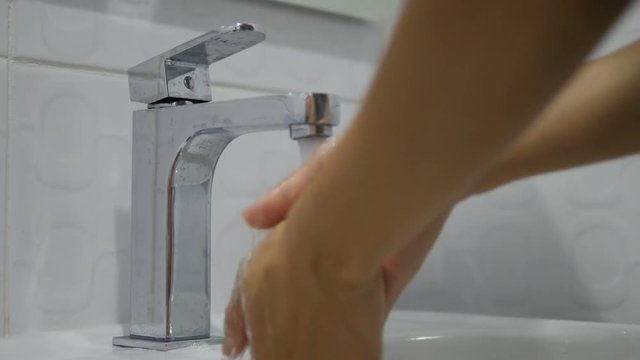 4K: Female hands washing under running water in a sink. Turning on tap, close up of adult hand turning on water and turning it off