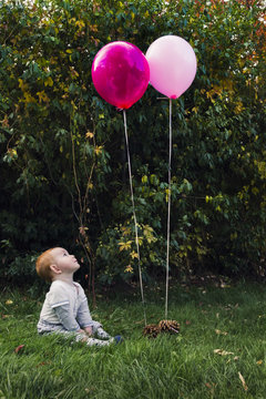 Cute readhead baby boy, playing with balloons outdoors