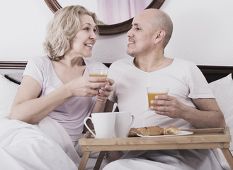 Mature couple having breakfast in bed.