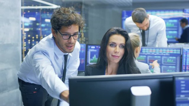 Professional Broker Consults Stock Exchange Trader at Her Workstation. Multi-Ethnic Team at Stock Exchange Office is Busy Selling and Buying Stocks on the Market. 